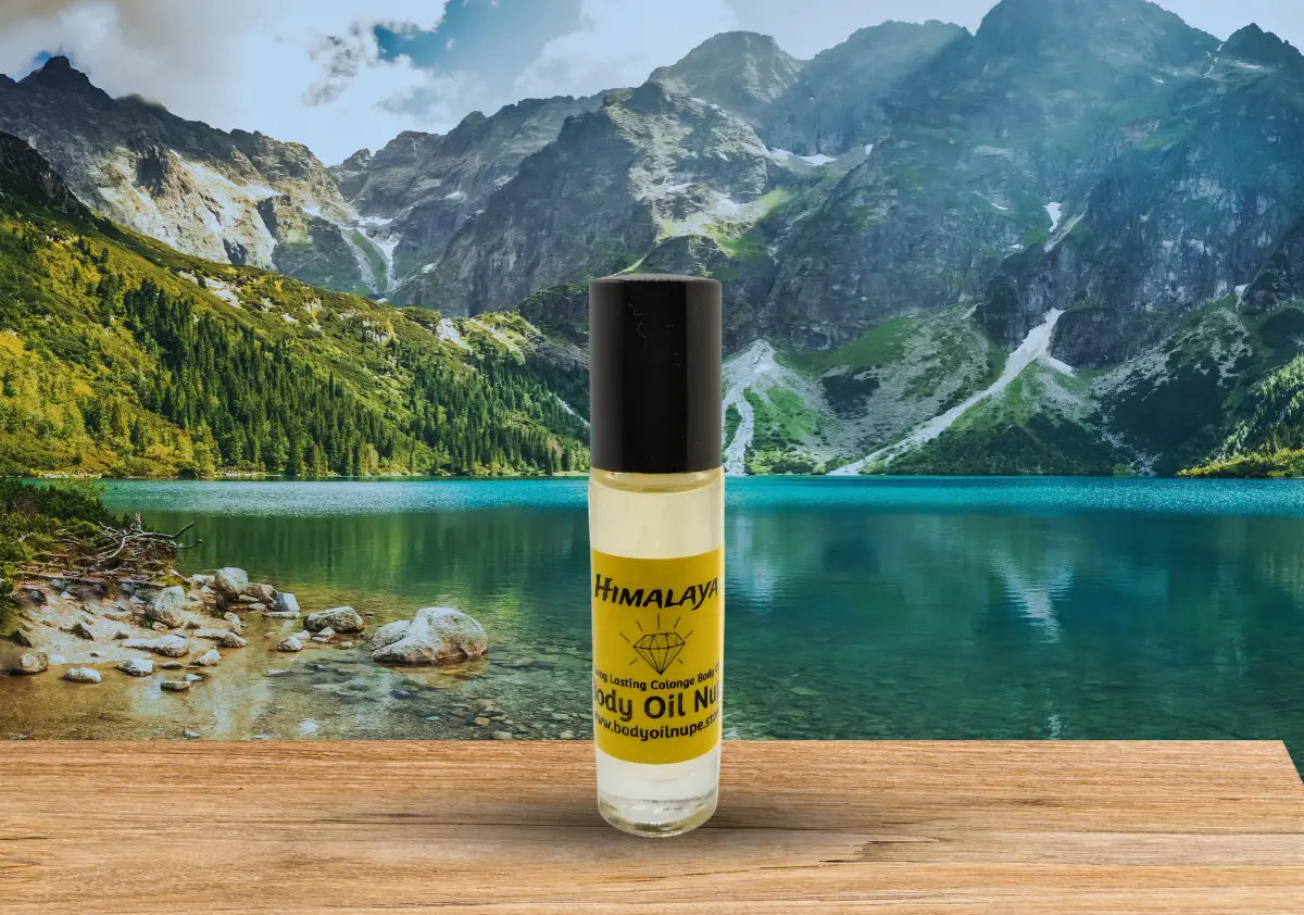 Himalaya body oil bottle displayed in front of a turquoise mountain lake and rugged peaks to evoke fresh, pure, and outdoors‑inspired fragrance notes. A yellow scent inside of glass bottle.
