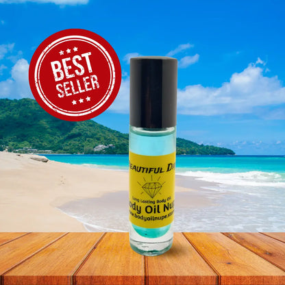 Beautiful Day body oil fragrance by Body Oil Nupe. Light blue scent inside of glass bottle sitting at beach with wood table background. Best Seller label for long-lasting body oil scent. 