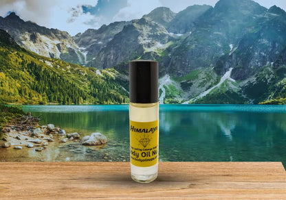 Himalaya body oil bottle displayed in front of a turquoise mountain lake and rugged peaks to evoke fresh, pure, and outdoors‑inspired fragrance notes.  A yellow scent inside of glass bottle. 