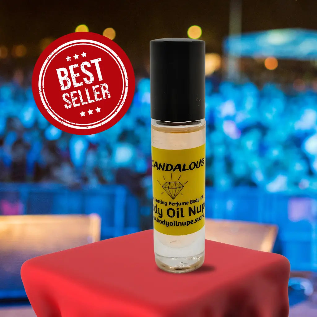 Scandalous body oil by Body Oil Nupe. Light orange long-lasting body oil fragrance inside glass bottle with black top on top of red table cloth. Background is crowd at concert