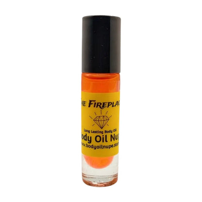 A small, clear rollerball bottle of 'The Fireplace' body oil with a black lid and a label featuring red and orange colors, indicating the scent of amber.